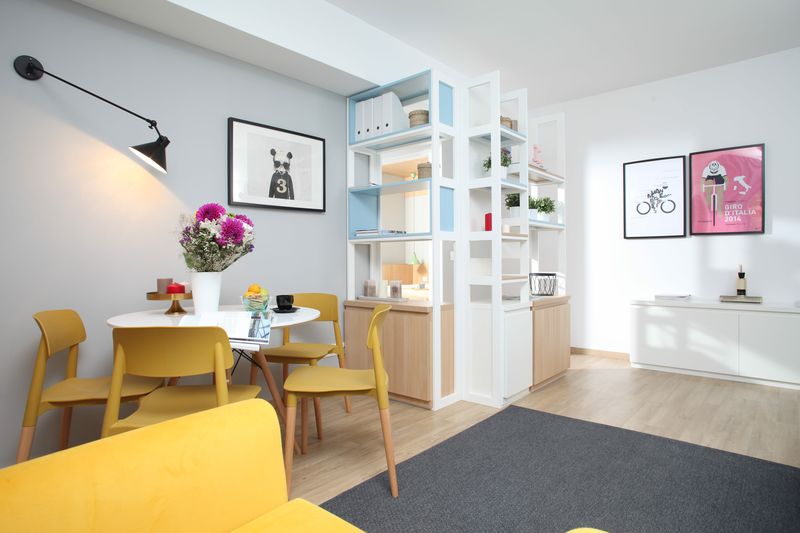 O organizare foarte inspirată a spațiului din living
a permis conturarea unei mici zone-dining, cu masă rotundă de la Domicilio și scaune de la ioooi.ro, valorificarea spațiului de sub grindă prin plasarea unei etajere multifuncționale, realizată la comandă prin Delta Studio, și conturarea unui loc de relaxare format din canapeaua albă de la IKEA și fotoliul galben de la MaisonDeco. Foto: Sorin Iacob